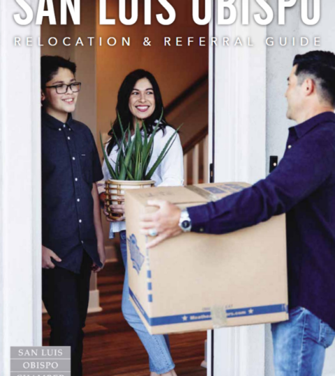 2022 Relocation & Referral Guide Cover - A mother and son stand smiling in the front doorway of their house while the father steps into the frame holding a moving box.