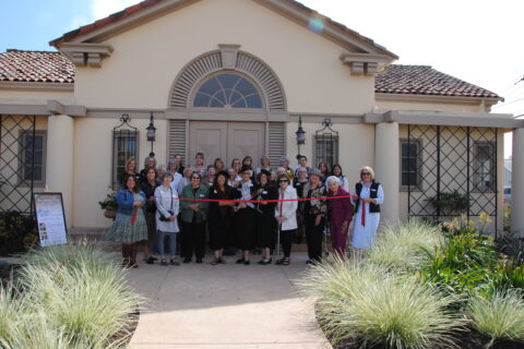 Group of people in front of The Monday Club taking photo for ribbon cutting