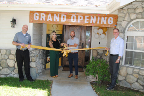 group photo of ribbon cutting in front of building