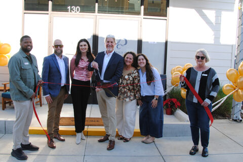 Group of people in front of Corrective Care Chiropractic office posing for ribbon cuting photo.