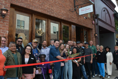 group photo of ribbon cutting outside and infront of brick building in SLO.
