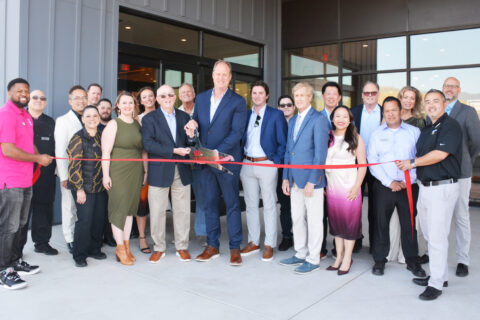 Group of people posting for a ribbon cutting ceremony.