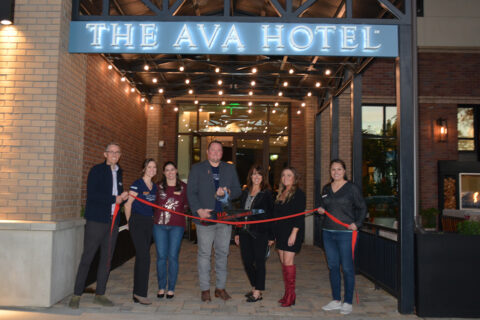 Group of people celebrating with a ribbon cutting in front of The Ava Hotel in Paso Robles, California.