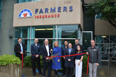 Group photo of ribbon cutting in front of Farmer's Insurance at their new location.