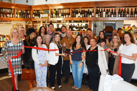 Group photo of ribbon cutting inside restaurant, Nicola