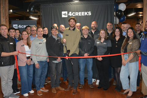 large group photo of people in front of a red ribbon getting ready to cut ribbon in celebration of their business, 4 Creeks.