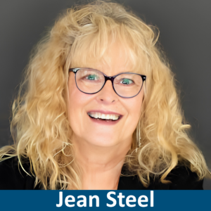 Picture of Jean Steel smiling, wearing black rimmed glases